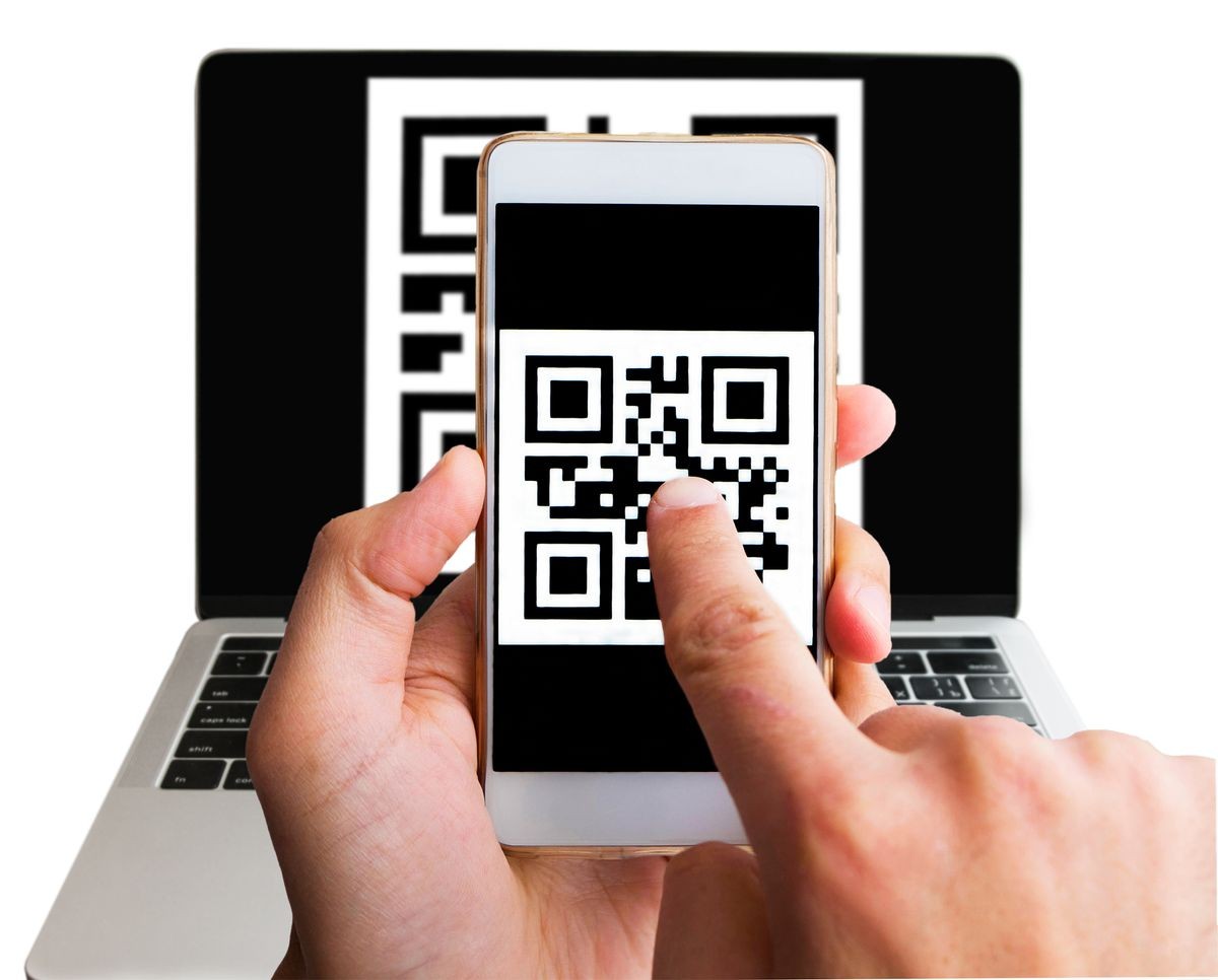 Scanning barcode from laptop using smartphone, close up. Two man hands holding phone and pointing on the qr code on the screen. Isolated on white. Internet cashless purchase